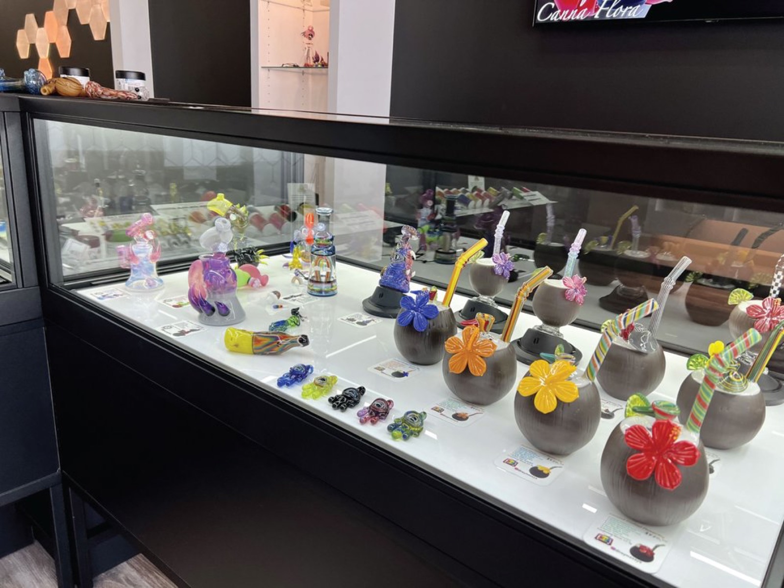 Glass pipes and gear on a lit shelf at Canna Flora