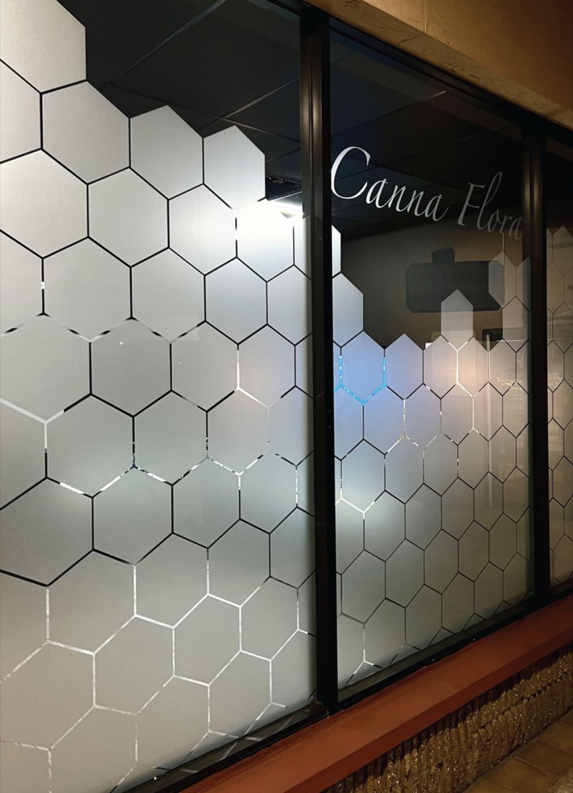 Canna Flora's hexagonal frosted-glass wall etched with the logo